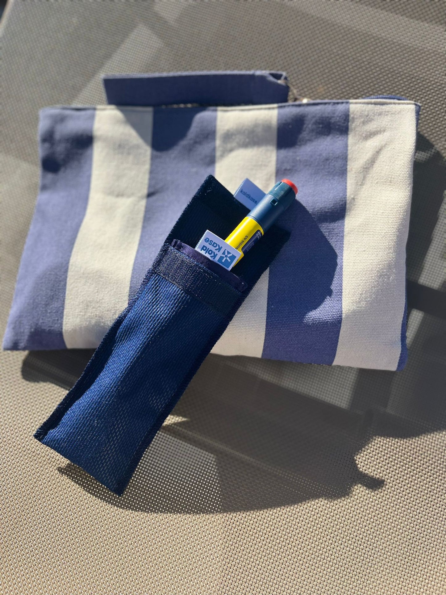 estuche térmico porta insulina 1 pluma azul encima de un neceser